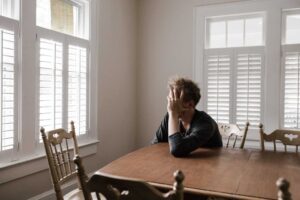 lonely man sitting at kitchen table with head in hands