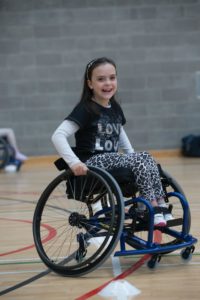 young girl sitting in a wheelchair on a basketball court