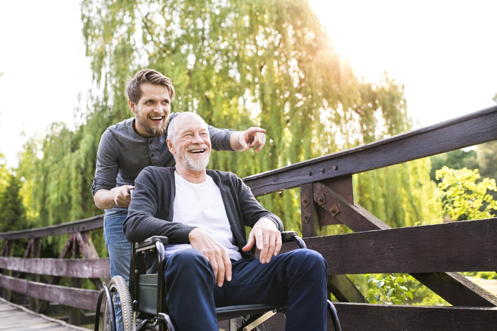 Two man smiling while the other is in the wheelchair(NDIS).