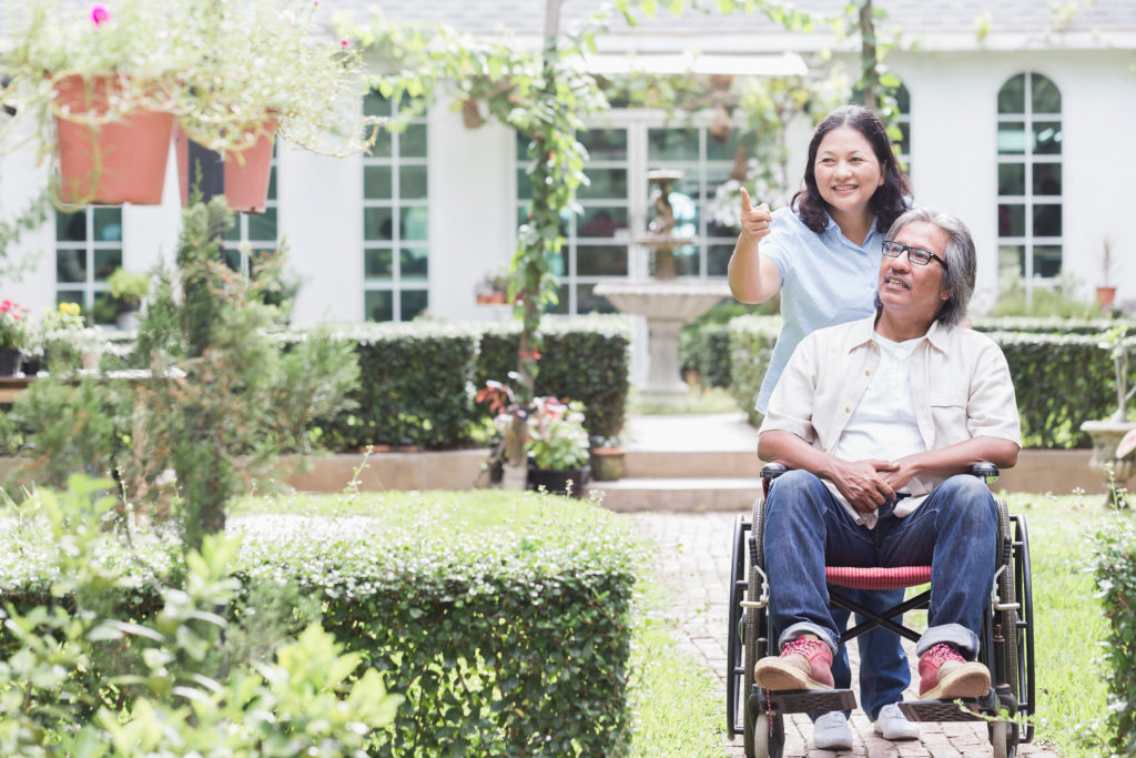 Senior,Woman,Walking,With,Disabled,Father,In,Garden.,Happy,Asian