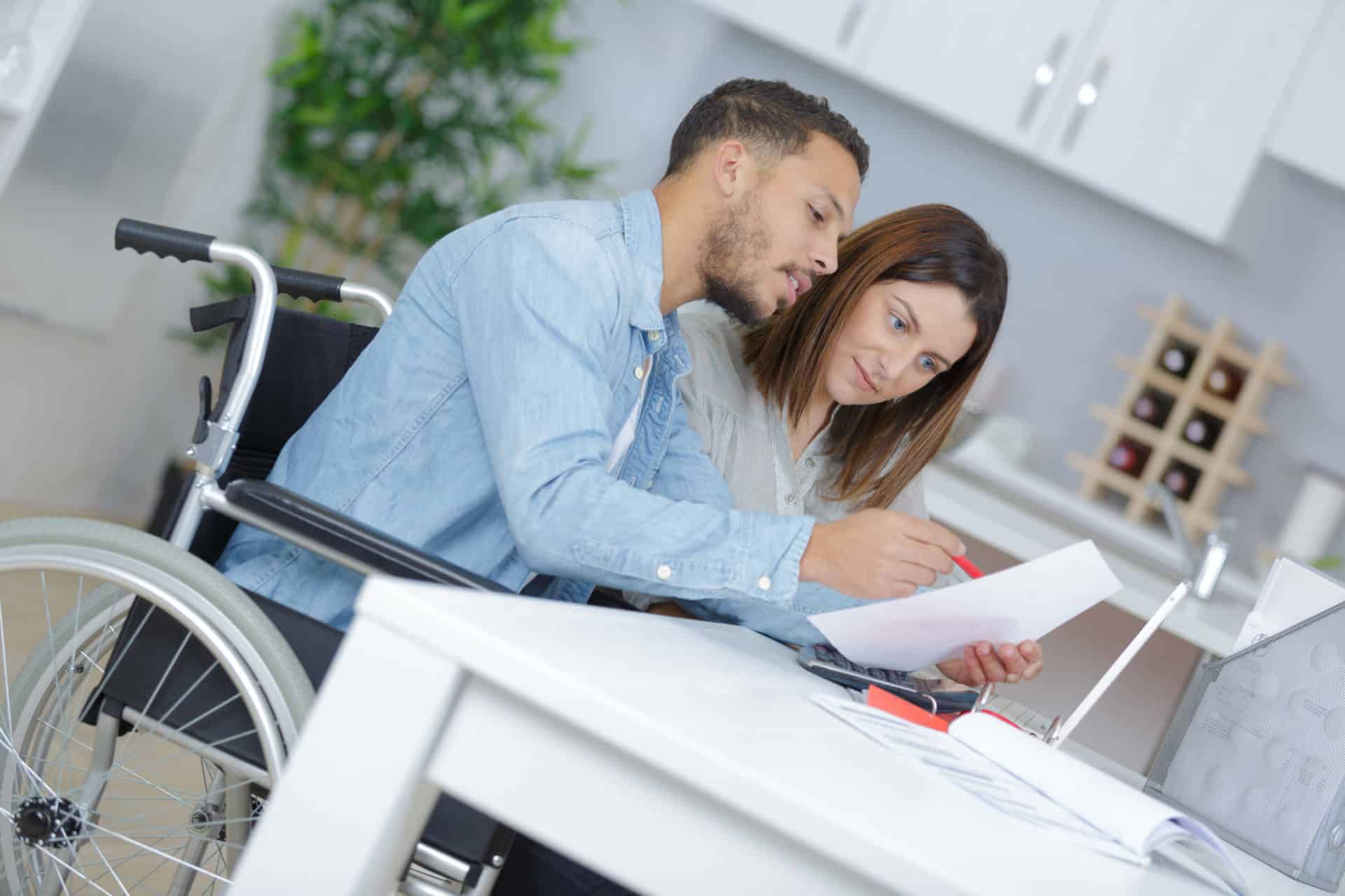 Man,In,Wheelchair,Talking,To,Woman,Cleaning,Kitchen