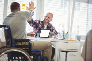 a person in a wheelchair giving a high five to another person representing NDIS.